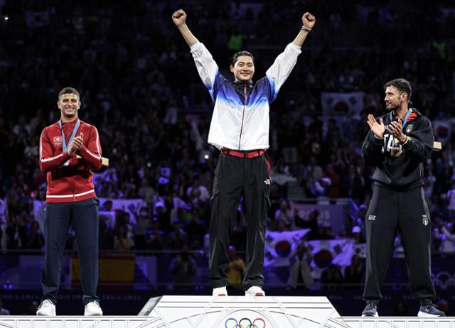 한국 펜싱 간판 오상욱(가운데)이 28일(한국시간) 프랑스 파리 그랑 팔레에서 열린 2024 파리올림픽 펜싱 남자 사브르 개인 결승 시상식에서 가장 높은 시상대에 올라 두 팔을 들어 보이고 있다. 파리=뉴스1