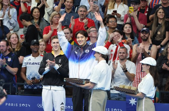 김우민이 27일(현지시간) 파리 라 데팡스 아레나에서 열린 2024 파리 올림픽 수영 자유형 남자 400ｍ 동메달을 딴 뒤 시상대에 올라 두 팔을 흔들며 기뻐하고 있다. 파리=올림픽사진공동취재단