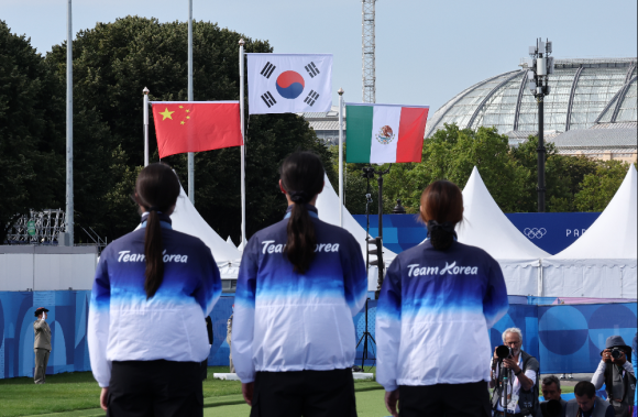 올림픽 10연패를 달성한 한국 여자 양궁대표팀의 남수현(왼쪽부터), 임시현, 전훈영이 28일(현지시간) 프랑스 파리 레쟁발리드 양궁 경기장에서 열린 2024 파리올림픽 양궁 여자단체 시상식에서 태극기가 게양되는 동안 국기에 경례하고 있다. 2024.7.29 연합뉴스