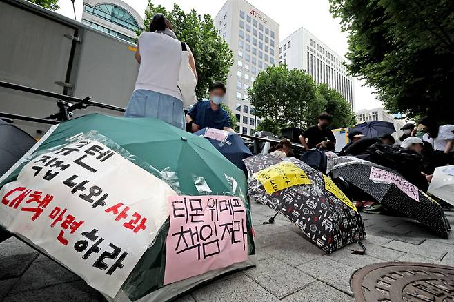 티몬과 위메프의 정산·환불 지연 사태가 지속되고 있는 28일 오후 서울 강남구 큐텐 본사 앞에서 피해자들이 사태 해결을 촉구하는 문구를 우산에 붙이며 시위를 준비하고 있다. /뉴스1