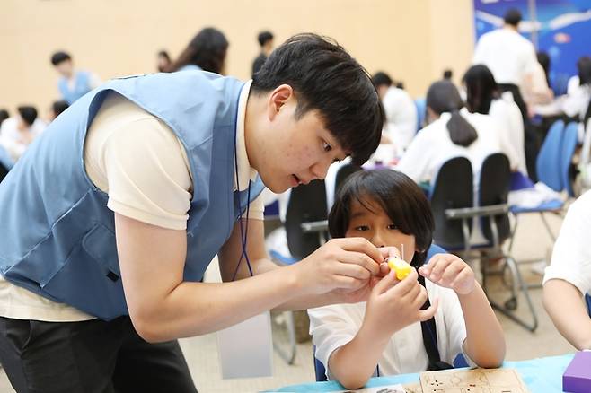 포스코퓨처엠 직원이 30일 포항 포스코 본사 대강당에서 열린 '푸른꿈 환경캠프'에 멘토로 나서 어린이와 함께 전기차 모형을 제작하고 있다. (포스코퓨처엠 제공)