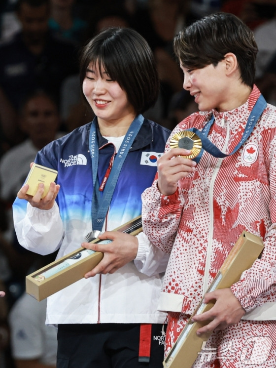 대한민국 유도대표팀 허미미 선수가 30일(한국시간) 프랑스 파리 샹 드 마르스 아레나에서 열린 2024 파리올림픽 유도 여자 -57kg 시상식에서 은메달을 수여 받은 후 수상자들과 기념촬영을 하기 위해 갤럭시 Z플립6를 건네 받고 있다. /사진=뉴스1