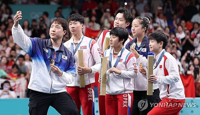 남북, 시상대에서 만나 '빅토리 셀피' (파리=연합뉴스) 김도훈 기자 = 30일(현지시간) 프랑스 파리 사우스 파리 아레나4에서 열린 2024 파리올림픽 탁구 혼합복식 시상식에서 동메달을 차지한 한국 임종훈, 신유빈과 은메달을 차지한 북한 리정식, 김금용 등이 시상대에서 삼성 Z플립 6로 함께 기념촬영을 하고 있다. 2024.7.30 superdoo82@yna.co.kr