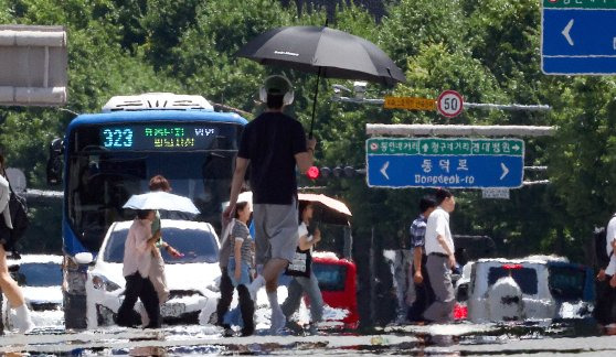 People cross a street in Jung District, Daegu, on Monday. A heat wave warning has been issued in the area. [YONHAP]