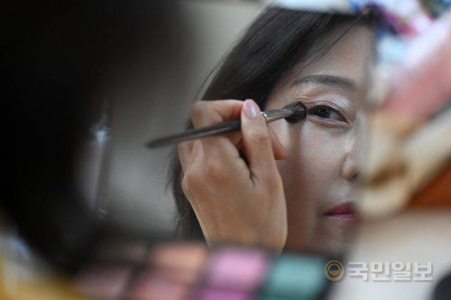 한 시니어 모델이 메이크업을 수정하고 있다.