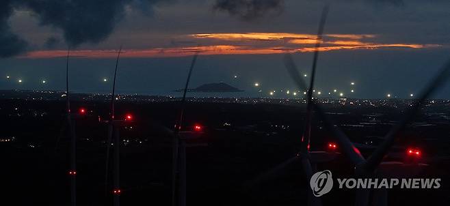 해질녘 제주 바다 밝히는 한치잡이 어선들 (제주=연합뉴스) 제주시 애월읍 어음풍력발전단지에서 바라본 비양도 인근 바다에 한치잡이 어선들이 환하게 불을 밝히고 있다. [연합뉴스 자료사진]