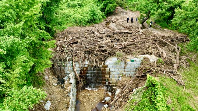 지난달 30일 전북 익산시 함라면 함라산 자락 사방댐 상류 계곡을 하늘에서 내려다본 모습. 산사태로 쏟아진 토석류와 뿌리째 뽑혀 떠내려온 나무들이 사방댐 위로 가득 차 있다.  산림청 제공