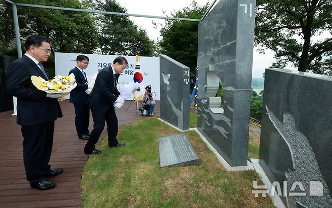 [파주=뉴시스] 고범준 기자 = 김영호 통일부 장관이 1일 오전 경기 파주시 탄현면 오두산 전망대 뒤뜰에서 열린 북한이탈주민의 날 기념 조형물 제막식에서 헌화 하고 있다. 왼쪽부터 태영호 민주평화통일자문회의 사무처장, 김 장관, 지성호 전 국회의원. 2024.08.01. bjko@newsis.com