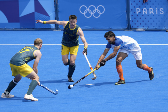 India's Abhishek Abhishek, right, battles for the ball with Australia's Eddie Ockenden, center, and Aran Zalewski during the men's field hockey match at the Yves-du-Manoir Stadium in Colombes, France om Friday. [AP/YONHAP]