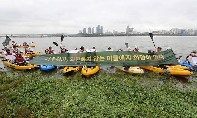 서울환경연합과 청년기후긴급행동 회원들이 2022년 6월15일 한강변 초고층 건축, 수변감성도시 등 난개발 정책에 반대하고 생물다양성 보호 정책 등을 촉구한 뒤 한강에서 카누를 타고 현수막을 들어 보이고 있다. 신소영 기자 viator@hani.co.kr