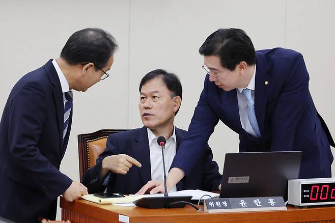 국회 정무위원회 전체회의에서 윤한홍 위원장(가운데)이 여야 간사들과 대화를 나누는 모습. [사진=연합뉴스]