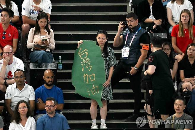 대만 응원 배너를 든 관중 옆에서 경호 요원이 무선 지시를 받는 모습.  [AFP=연합뉴스]