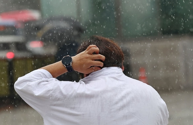 오늘(7일) 오전 서울 보신각 앞에서 한 시민이 소나기를 맞으며 걸어가고 있다. / 사진=연합뉴스