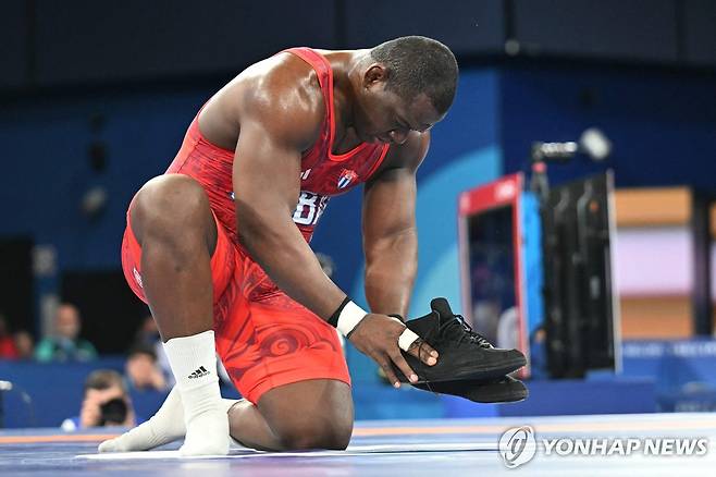 매트에 신발을 놓는 올림픽 최초 5연패 레슬링 선수 로페스 [AFP=연합뉴스]