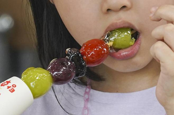 과일꼬치에 설탕시럽을 입힌 중국 전통 간식 ‘탕후루’를 먹는 모습. 어린이, 청소년이 즐겨 먹는 간식인 탕후루에 함유된 당류는 14~27g에 달한다. 쿠키뉴스 자료사진