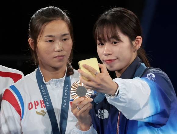 2024 파리 올림픽 복싱 여자 54㎏급에서 동메달을 획득한 우리나라 임애지(오른쪽)와 북한 방철미가 8일(현지시간) 프랑스 파리 롤랑가로스 경기장에서 열린 시상식에서 ‘셀카 세리머니’를 하고 있다. 2024.8.9 연합뉴스
