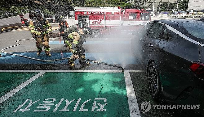 '전기차 화재 진압은 이렇게' (대구=연합뉴스) 윤관식 기자 = 26일 대구 서구 이현동 대구서구문화회관에서 진행된 전기차 화재 대응 훈련에서 대구서부소방서 소방관이 상방방사장치를 사용해 불을 끄는 훈련을 하고 있다. 2024.6.26 psik@yna.co.kr