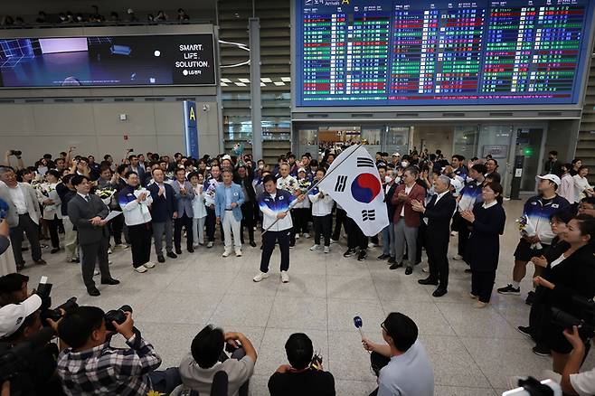 정강선 파리 올림픽 대한민국 선수단장이 13일 오후 인천국제공항 제2여객터미널을 통해 귀국해 태극기를 휘날리고 있다. 사진 | 영종도=연합뉴스