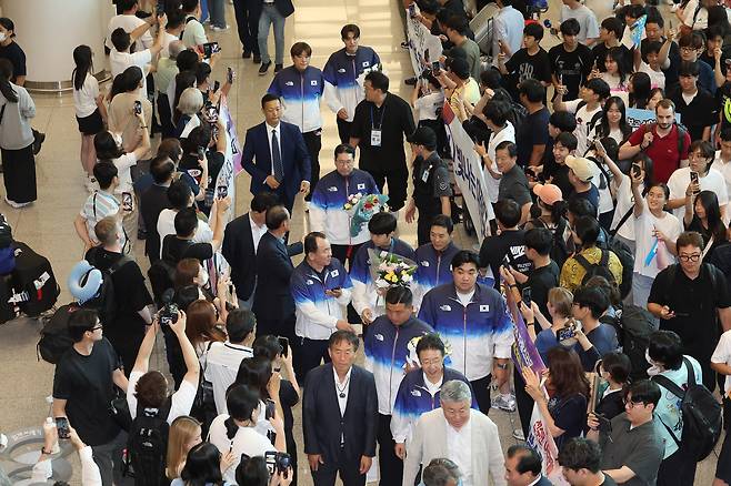 People crowd Incheon International Airport on Tuesday as Korean athletes, center, return home from Paris. Korea finished eighth with 32 medals — 13 gold, nine silver and 10 bronze — which came despite the country sending its smallest delegation to the Olympics since 1976. The number of gold medals matched the standing record, with Korea having won 13 apiece at the 2008 and 2012 Olympics. [YONHAP]