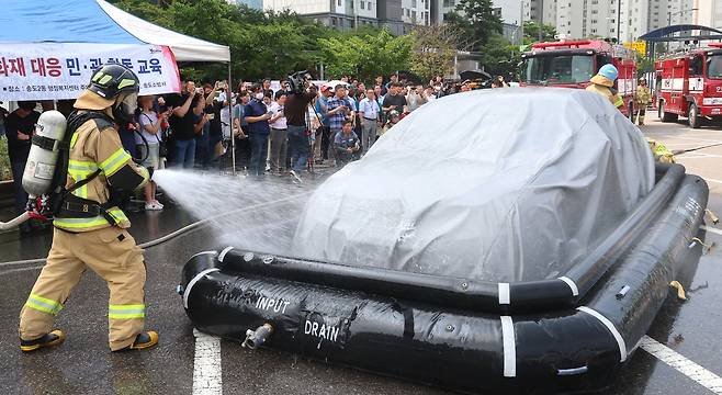 전기차 화재 진압 시연 - 13일 인천 연수구가 송도2동 행정복지센터 주차장에서 진행한 '전기차 화재 대응 민관 합동 교육'에서 소방관들이 질식 소화포와 전기차용 수조 탱크를 이용해 전기차 화재를 진압하는 시연을 하고 있다. 이달 초 인천 청라의 벤츠 전기차 화재 사건 이후 전기차 배터리에 대한 소비자 불안감이 커지자, 자동차 회사들은 잇따라 배터리 제조사 내역을 공개하고 있다. /연합뉴스