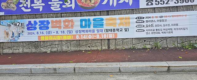 ▲12일 태백시 상장동 현수막 거치대에 부착되어 있는 상장벽화마을축제 안내 현수막. 함태중학교 앞에서 개최하려던 벽화마을축제 장소가 일부 주민들의 반발로 인근 2차선 도로로 변경되었다. ⓒ프레시안