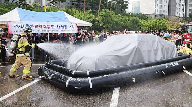 13일 오전 인천 연수구 송도 2동 행정복지센터 주차장에서 열린 전기자동차 화재대응 민·관 합동 교육에서 소방관들이 질식소화포와 전기차 수조탱크를 이용한 전기차 화재 진압 모의 시연을 하고 있다.