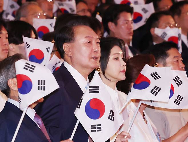 President Yoon Suk Yeol, center left, holds a the national flag of the Republic of Korea, also known as the Taegeukgi, next to first lady Kim Keon Hee, at the 79th Liberation Day ceremony, held at the Sejong Art Center in central Seoul on Thursday. (Yonhap)