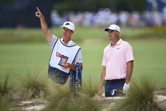 Scottie Scheffler, left, talks with his caddie Ted Scott while preparing to hit a shot from the bunker on the third hole during the first round of U.S. Open Championship at Pinehurst No. 2 at Pinehurst Resort on June 13 in Pinehurst, North Carolina. [GETTY IMAGES]