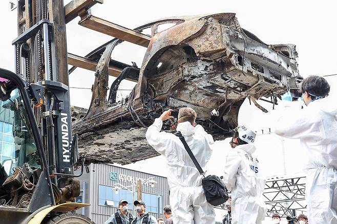 지난 8일 오전 인천 서구의 한 정비소에서 청라 아파트 지하주차장에서 발생한 화재로 전소된 전기차가 2차 합동감식을 받기 위해 지게차에 실려 정비소 내부로 향하고 있다. /뉴스1