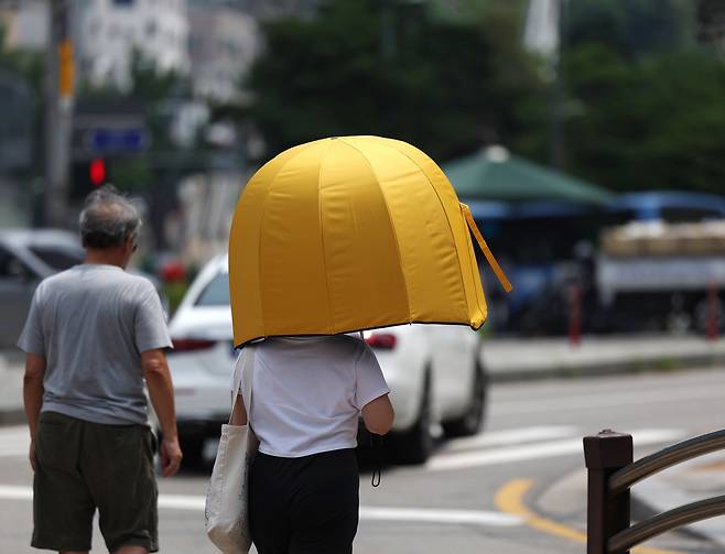 불볕더위가 이어진 서울 시내에서 한 시민이 우산을 쓰고 이동하고 있다. [연합]