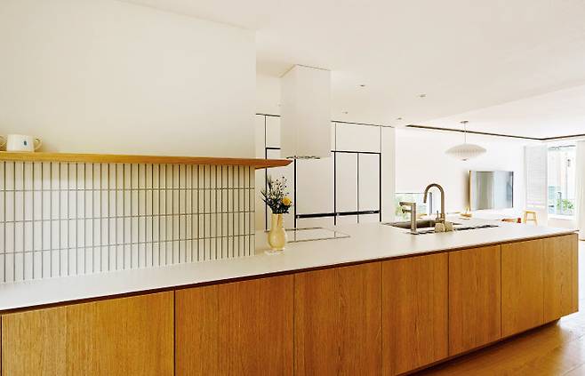 난간과 11자 형태가 되도록 길게 제작한 아일랜드 테이블. 그 밑으로 수납공간을 만든 덕에 살림살이를 모두 숨길 수 있다.