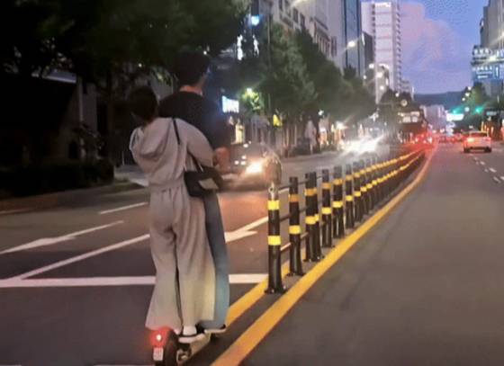 An image circulating online shows a couple riding an e-scooter the wrong way down a street without any protective gear, which has been receiving widespread criticism. [SCREEN CAPTURE]