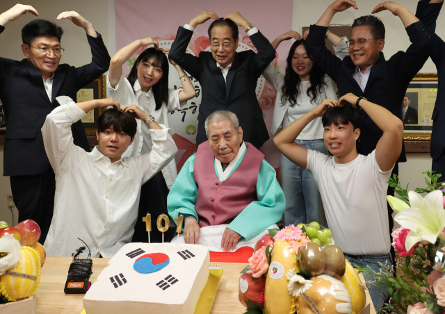 한덕수(뒷줄 가운데) 국무총리와 청년인턴들이 21일 수원시 장안구 보훈공단 보훈원을 방문해 오성규(앞줄 가운데) 애국지사의 101번째 생일을 축하하며 머리 위로 하트를 그려보이고 있다. 연합뉴스