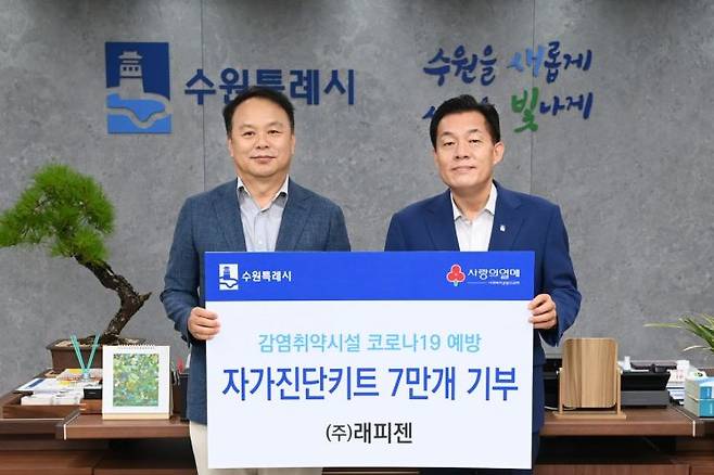 박재구 ㈜래피젠 대표(왼쪽)가 22일 이재준 수원시장에게 코로나19 자가진단키트 7만개를 전달한 뒤 기념사진을 찍고 있다.