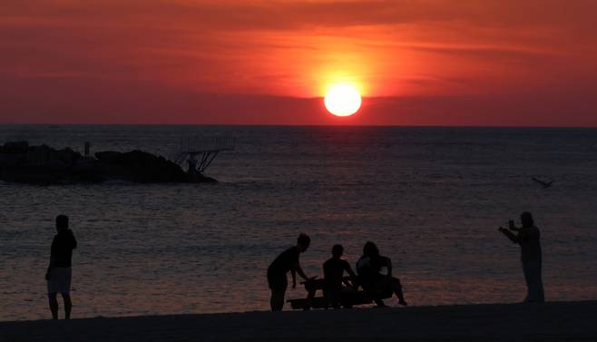 People watch the sunrise on the white sand of Gyeongpo Beach in Gangneung, Gangwon Province, South Korea on Friday. The Korea Meteorological Administration forecast the day's high temperature in Gangneung to reach 36 degrees. (Yonhap)