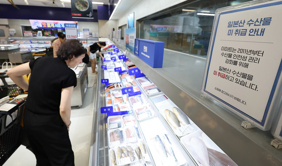 Customers shop in the seafood section of a discount store in Seoul, where a notice is displayed saying that the store does not sell marine products from Japan, on Wednesday. [NEWS1]