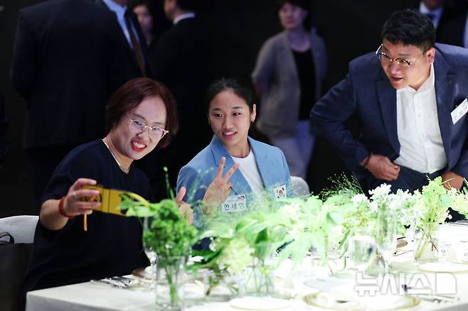 [서울=뉴시스] 최진석 기자 = 2024 파리올림픽 여자 배드민턴 단식 금메달리스트 안세영이 22일 서울 한 호텔에서 열린 2024 파리올림픽 선수단 격려 행사에 참석해 어머니 이현희 씨, 아버지 안정현 씨와 휴대전화로 사진을 찍고 있다. 2024.08.22. myjs@newsis.com