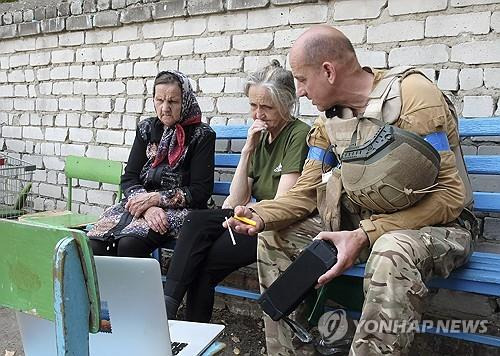 러시아 남서부 수드자 주민들이 진격해 들어온 우크라이나 병사 옆에 앉아 있는 모습 [EPA 연합뉴스 자료사진]