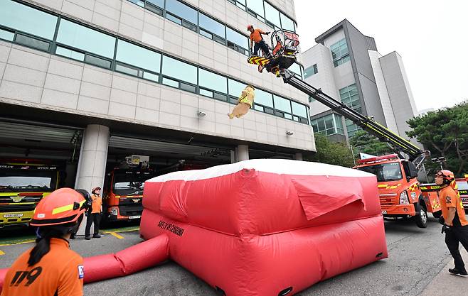 Fire authorities conduct a drill involving landing on an inflatable fire rescue mattress at the Gyeonggi Fire and Disaster Headquarters in Gwonseon District, Gyeonggi, on Monday. Concerns rose over the safety of firefighters' rescue mattresses after it was revealed that two of the seven victims in Thursday's Bucheon hotel fire died after jumping onto one while trying to escape. [JOINT PRESS CORPS]