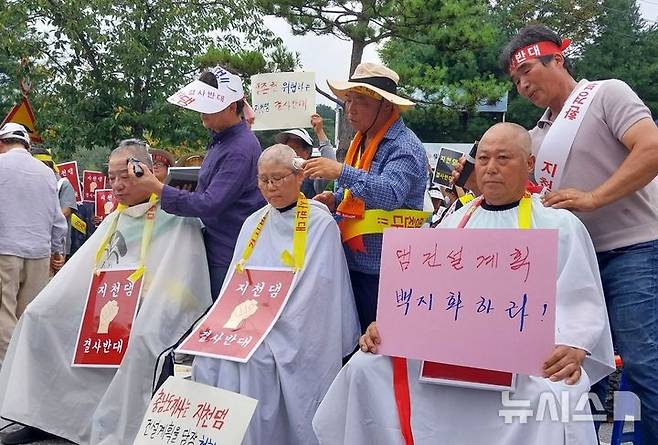 [청양=뉴시스] 조명휘 기자 = 청양 지천댐을 반대하는 대책위원회 주민들이 26일 오후 청양문예회관 앞에서 열린 시위에서 삭발을 하고 있다. 2024.08.26. photo@newsis.com