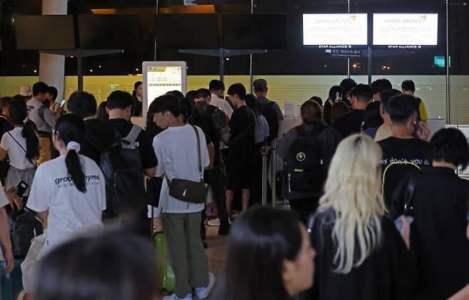 제주에서 김포로 갈 예정인 대한항공 항공기가 기체고장으로 활주로에 멈춰서면서 제주공항 항공기 운항이 전면 중단된 지난 26일 밤 서울 김포공항에서 항공편이 결항된 탑승객들이 대체항공편 문의를 위해 길게 줄지어 서 있다. (사진=연합뉴스)