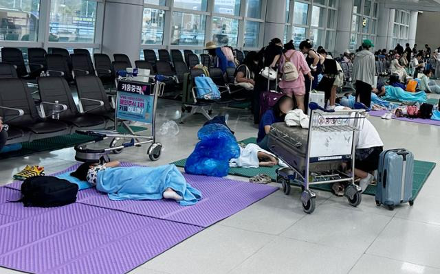 27일 오전 제주국제공항 국내선 출발층 대합실에서 간밤 결항 항공편 승객들이 매트 위에서 모포를 덮고 쪽잠을 자고 있다. 뉴스1