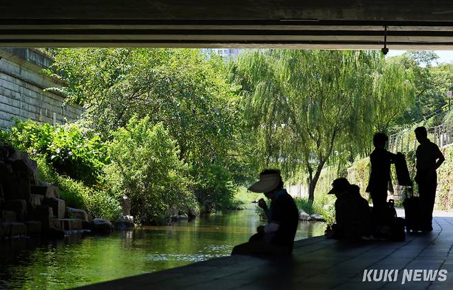 28일 서울 종로구 청계천에서 시민들이 그늘 아래로 들어가 더위를 피하고 있다.