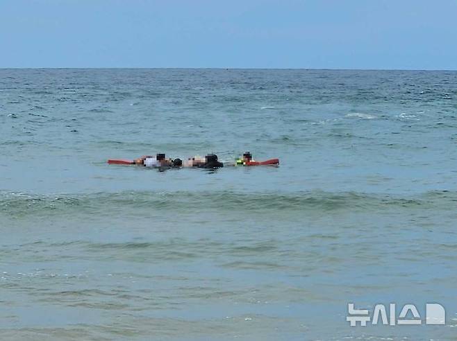 [고성=뉴시스] 30일 오후 1시46분께 강원 고성군 오호리 죽왕면 송지호해수욕장에서 해상 레저 활동 중, 3명이 바다에 빠져 해경이 구조하고 있는 모습. (사진=강원도소방본부 제공)