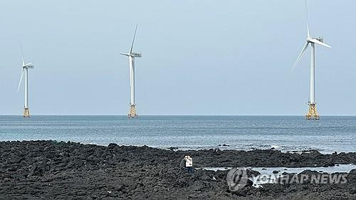 제주 한경면 해안의 풍력발전기를 배경으로 사진 찍는 관광객들 [촬영 차대운]