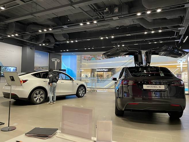 A visitor takes a look at a white Tesla Model Y on the left at the Tesla Store in Starfield Hanam, a shopping complex located in Gyeonggi Province just east of Seoul, Aug. 24. (Moon Joon-hyun/The Korea Herald)