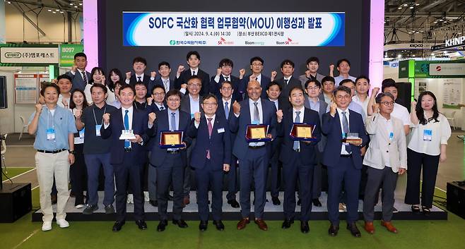 4일 부산 BEXCO에서 열린 SOFC 국산화 협력 이행성과 발표회에서 SK에코플랜트와 한국수력원자력, 블룸에너지, 블룸SK퓨얼셀 관계자들이 기념촬영을 하고 있다(앞줄 왼쪽 3번째부터 김정훈 SK에코플랜트 솔루션BU 대표, 윤상조 한국수력원자력 그린사업본부장, 사티시 치투리(Satish Chitoori) 블룸에너지 COO(Chief Operations Officer), 김세준 블룸SK퓨얼셀 부사장. [SK에코플랜트 제공]