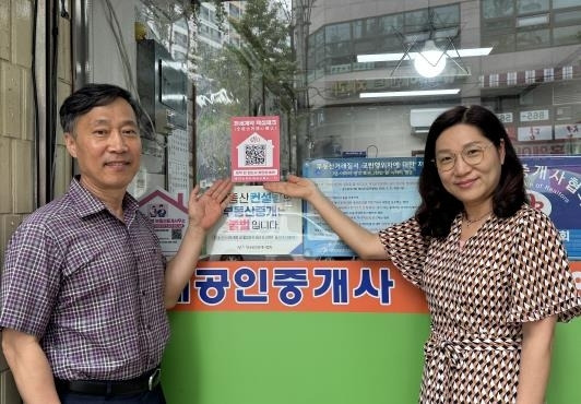 서울 구로구의 한 부동산중개업소가 ‘전세계약 핵심체크’ 큐알(QR)코드 스티커를 붙인 뒤 기념촬영을 하고 있다. 구로구 제공