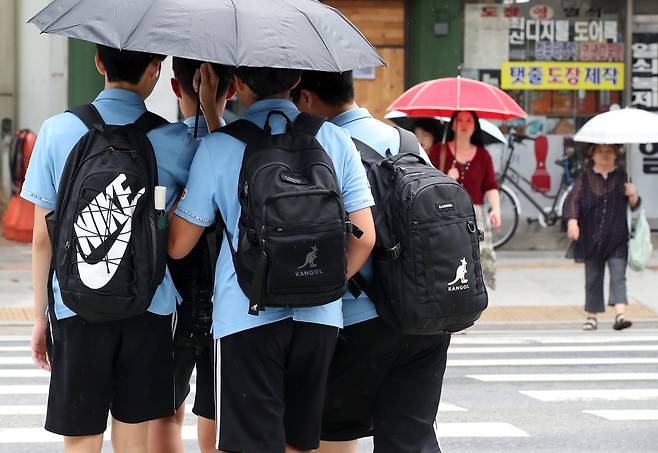 늦더위가 이어진 11일 오후 대구 중구 국채보상로 일대에 비가 내리자 하굣길 학생들이 우산 하나로 함께 비를 피하며 횡단보도를 건너고 있다. /뉴스1