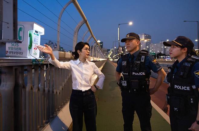 김건희 여사가 9월10일 '세계 자살 예방의 날'을 맞아 서울 마포대교에서 마포경찰서 용강지구대 근무자와 함께 '생명의 전화'를 살펴보며 대화하고 있다. ⓒ연합뉴스